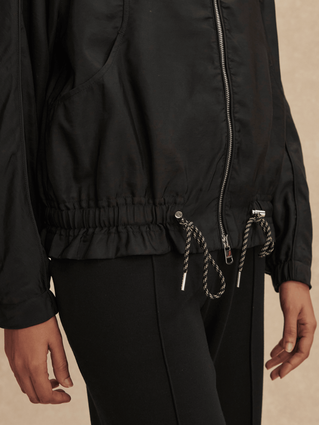 Person wearing a black jacket with a beige background
