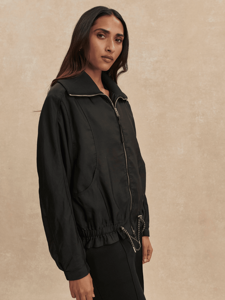 Woman wearing a black jacket against a beige background