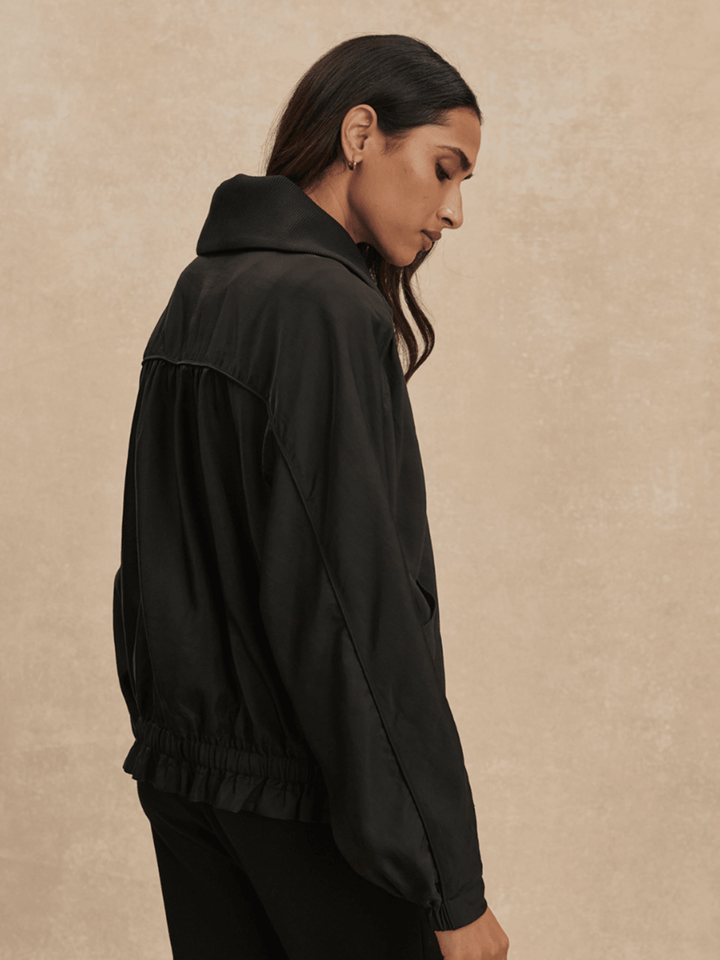 Woman wearing a black jacket against a beige background