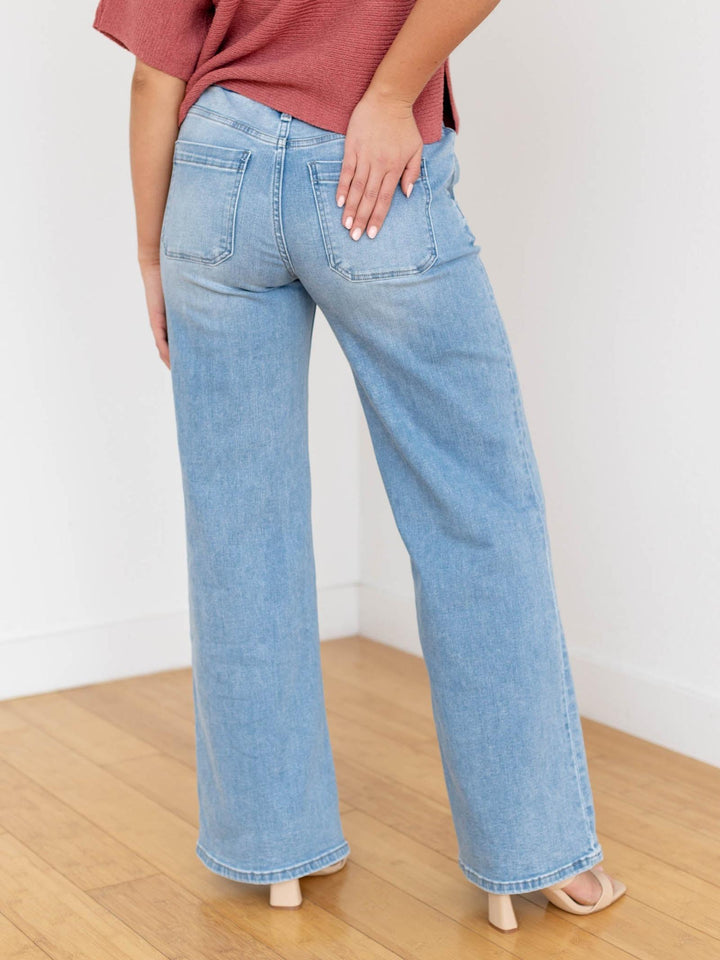 Woman wearing a rust-colored top and light blue jeans on a white background