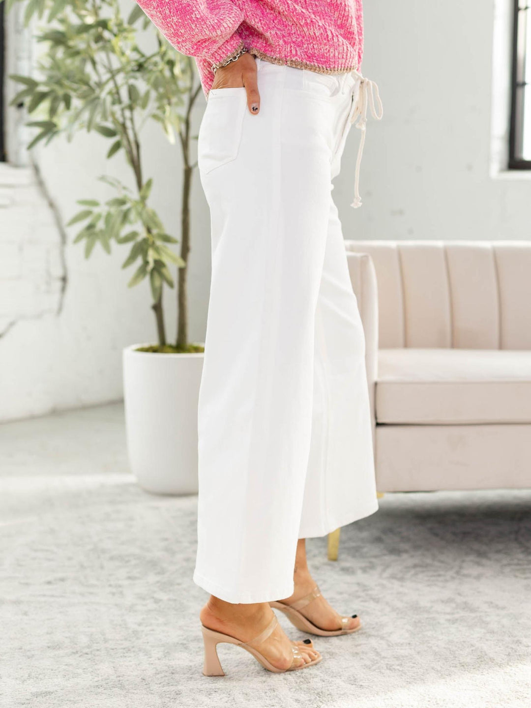 Person wearing white pants and a pink top in a living room setting