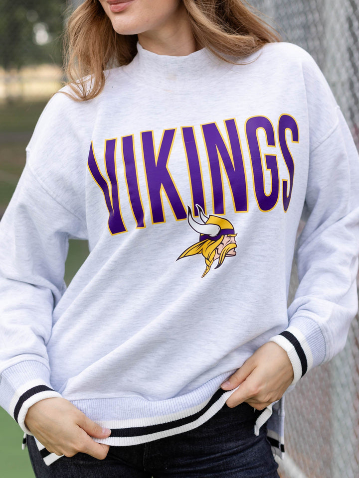 A woman wearing a light heather gray sweatshirt with &