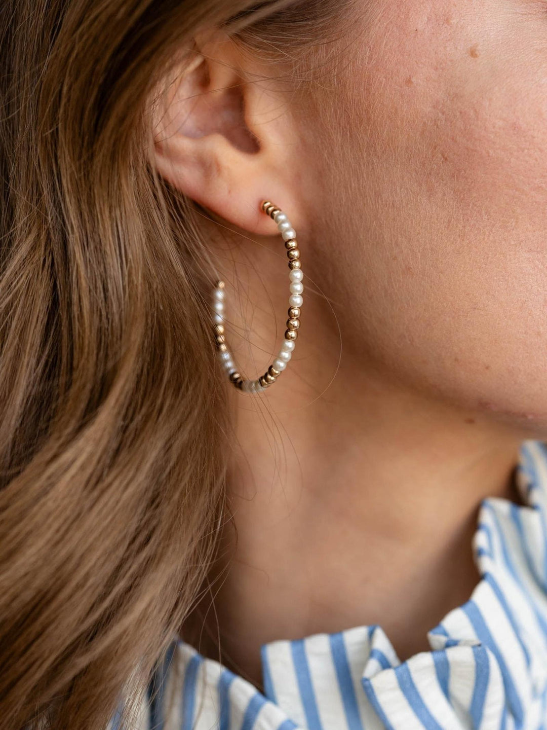 Close-up of an ear wearing a beaded earring with a blurred background