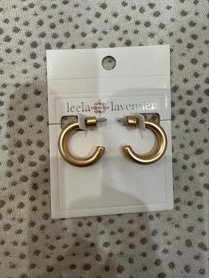 Gold hoop earrings on a Leela Lavender branded card against a textured background