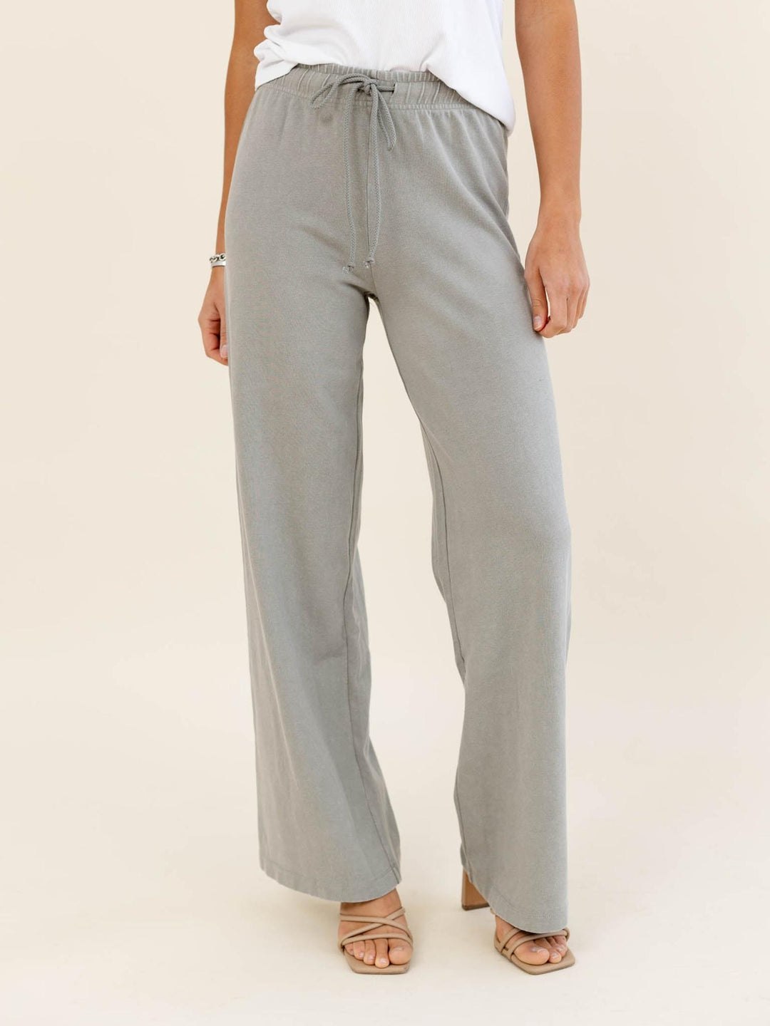 Person wearing light gray wide-leg pants on a beige background