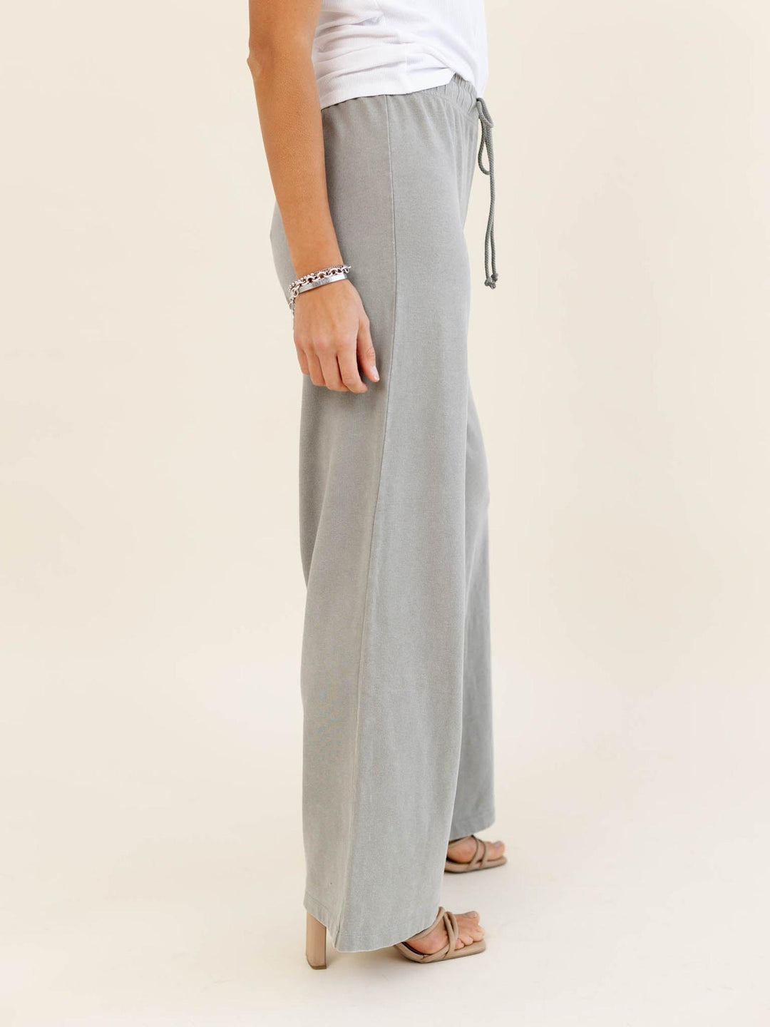 Light gray wide-leg pants worn by a person on a beige background