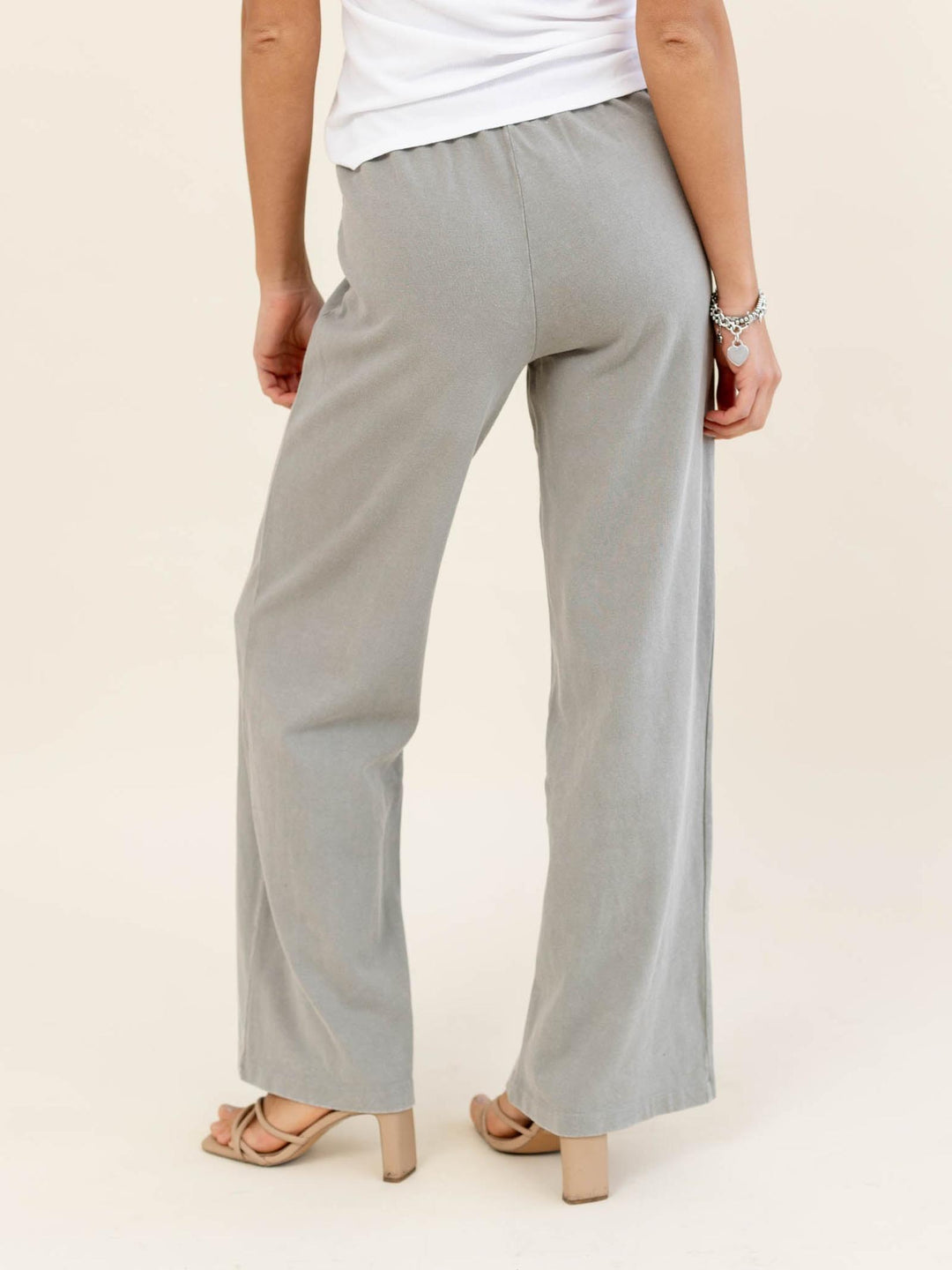 Person wearing light gray wide-leg pants on a plain background