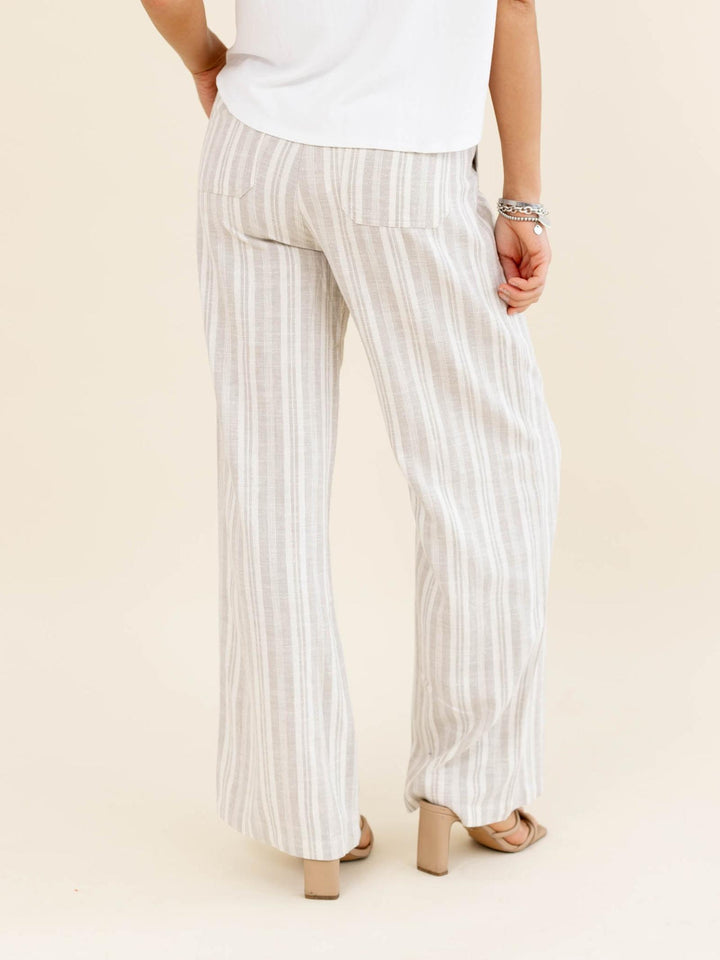 Person wearing white and gray striped pants on a beige background