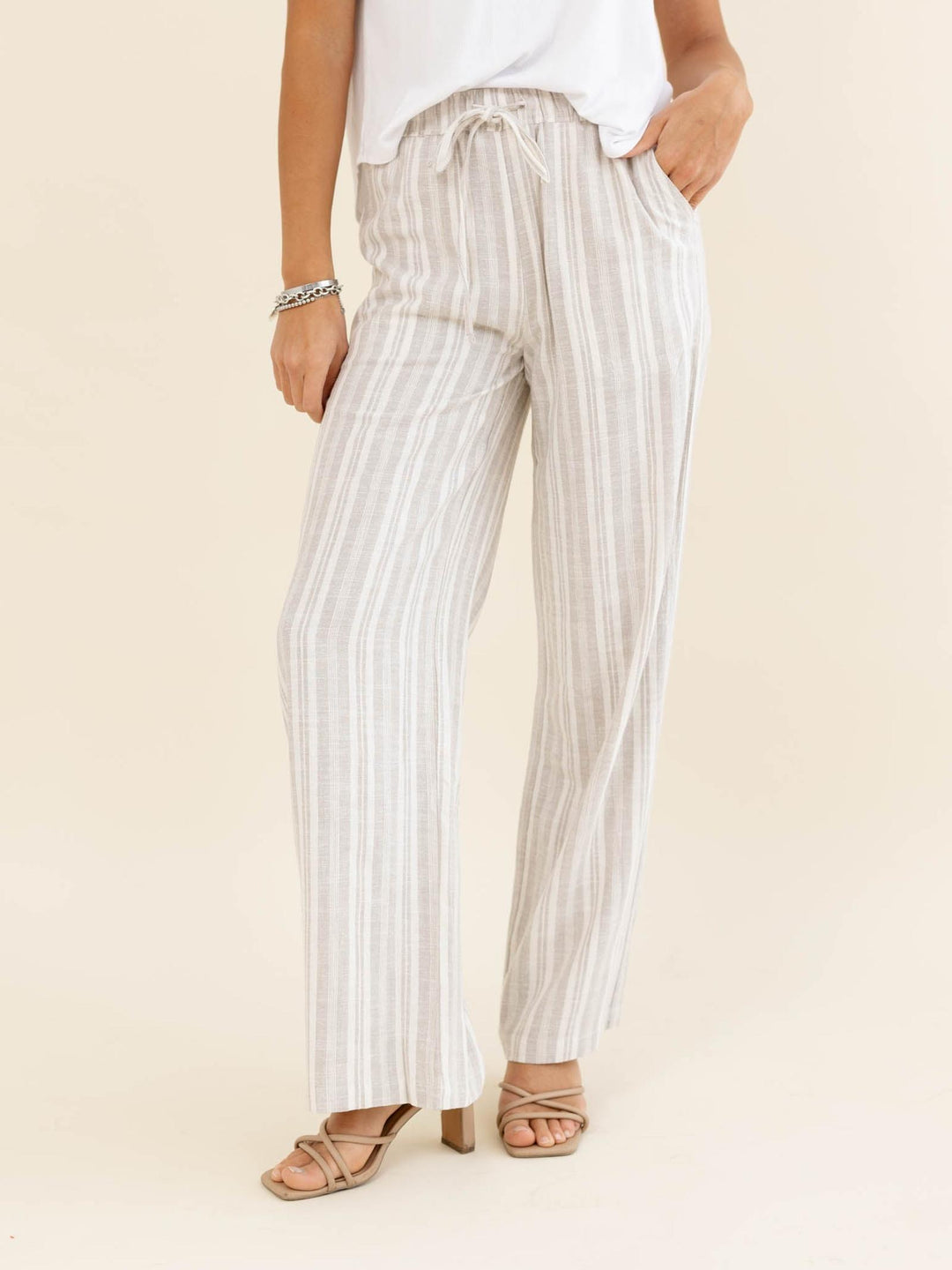 Person wearing white and gray striped pants on a beige background