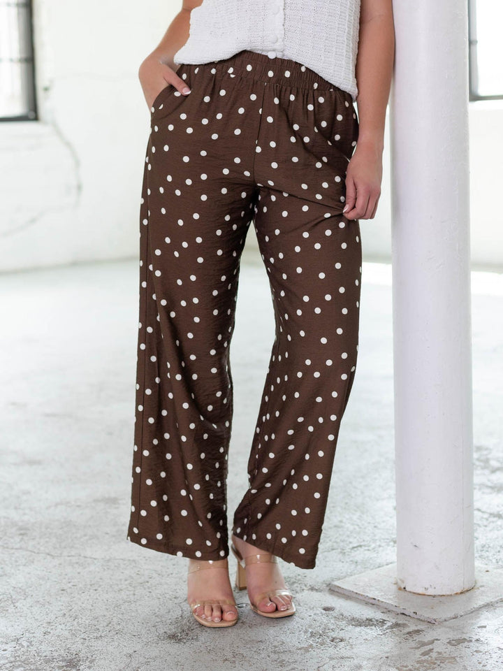 Brown woven wide-leg pants with white polka dots, elastic waistband, and side pockets.