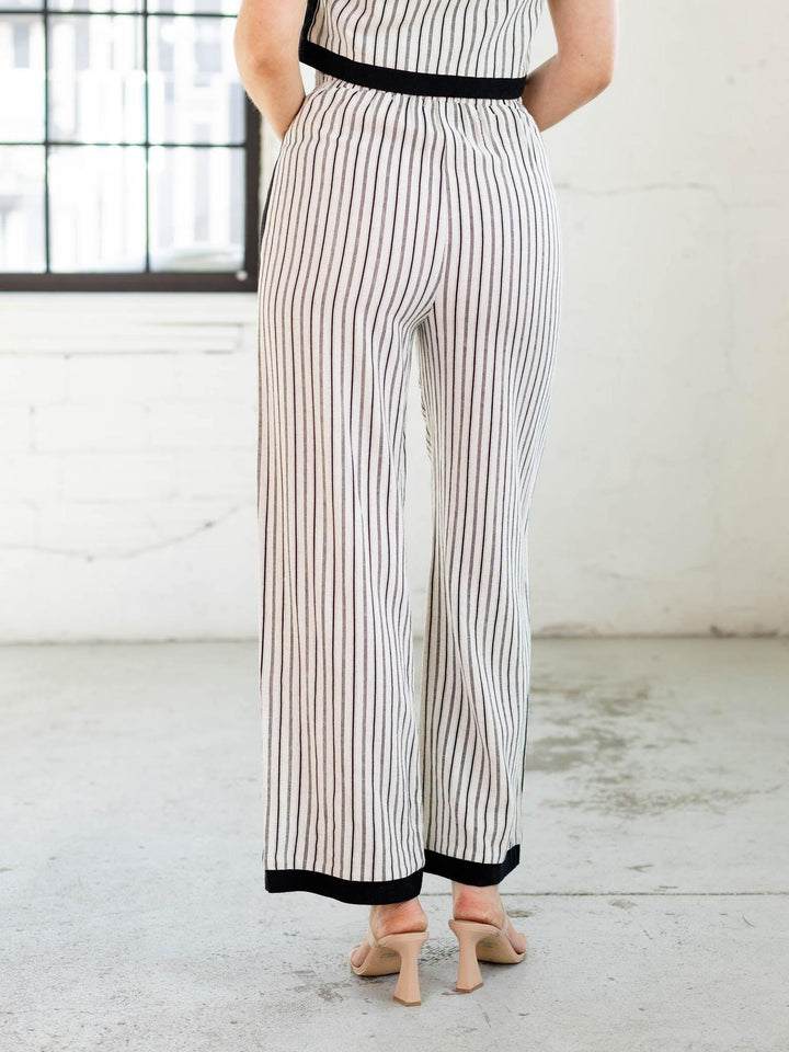 Person wearing a black and white striped jumpsuit in a minimal indoor setting.