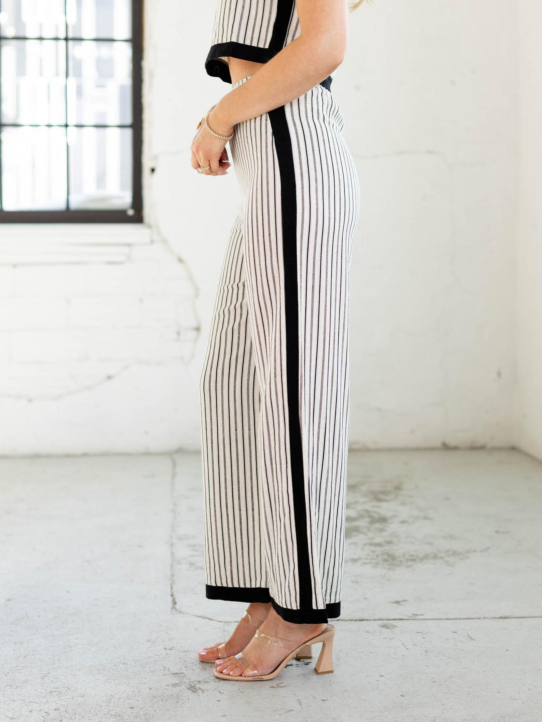 Person wearing black and white striped pants in a minimal indoor setting