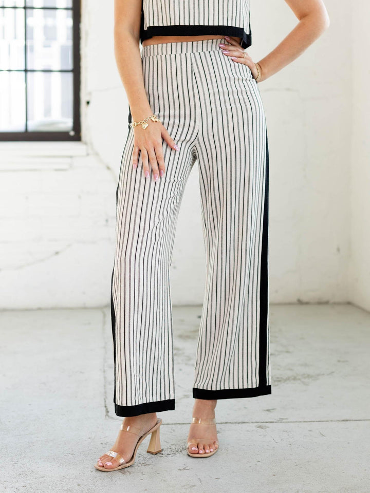Person wearing black and white striped pants with a plain background