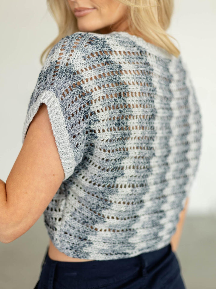 Person wearing a patterned knit top with a neutral background