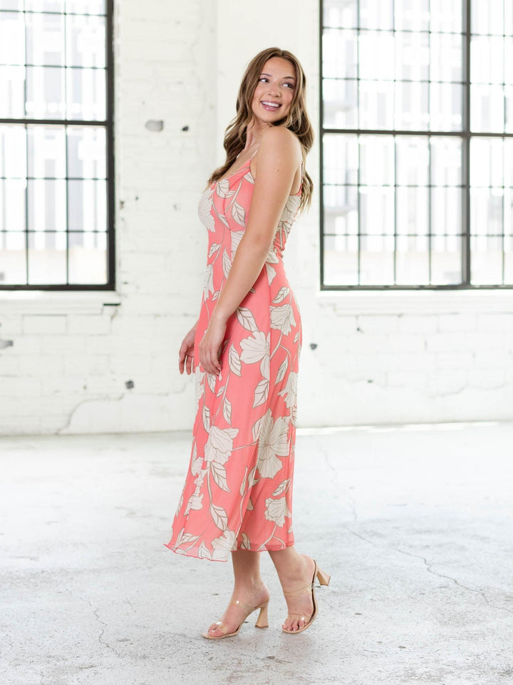 Woman in Z Supply Charisma Bloom Midi Dress, a coral floral mesh dress with thin straps and flowy skirt.