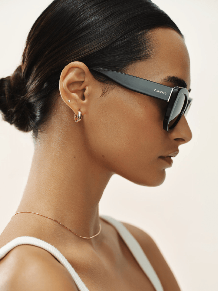 Woman wearing black sunglasses with a neutral background