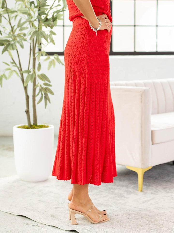 Person wearing a red textured dress in a room with a plant and sofa.