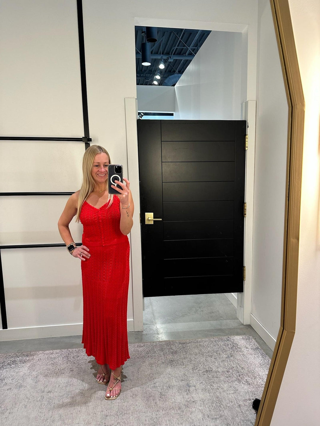 Woman in a red dress taking a mirror selfie in an indoor setting.