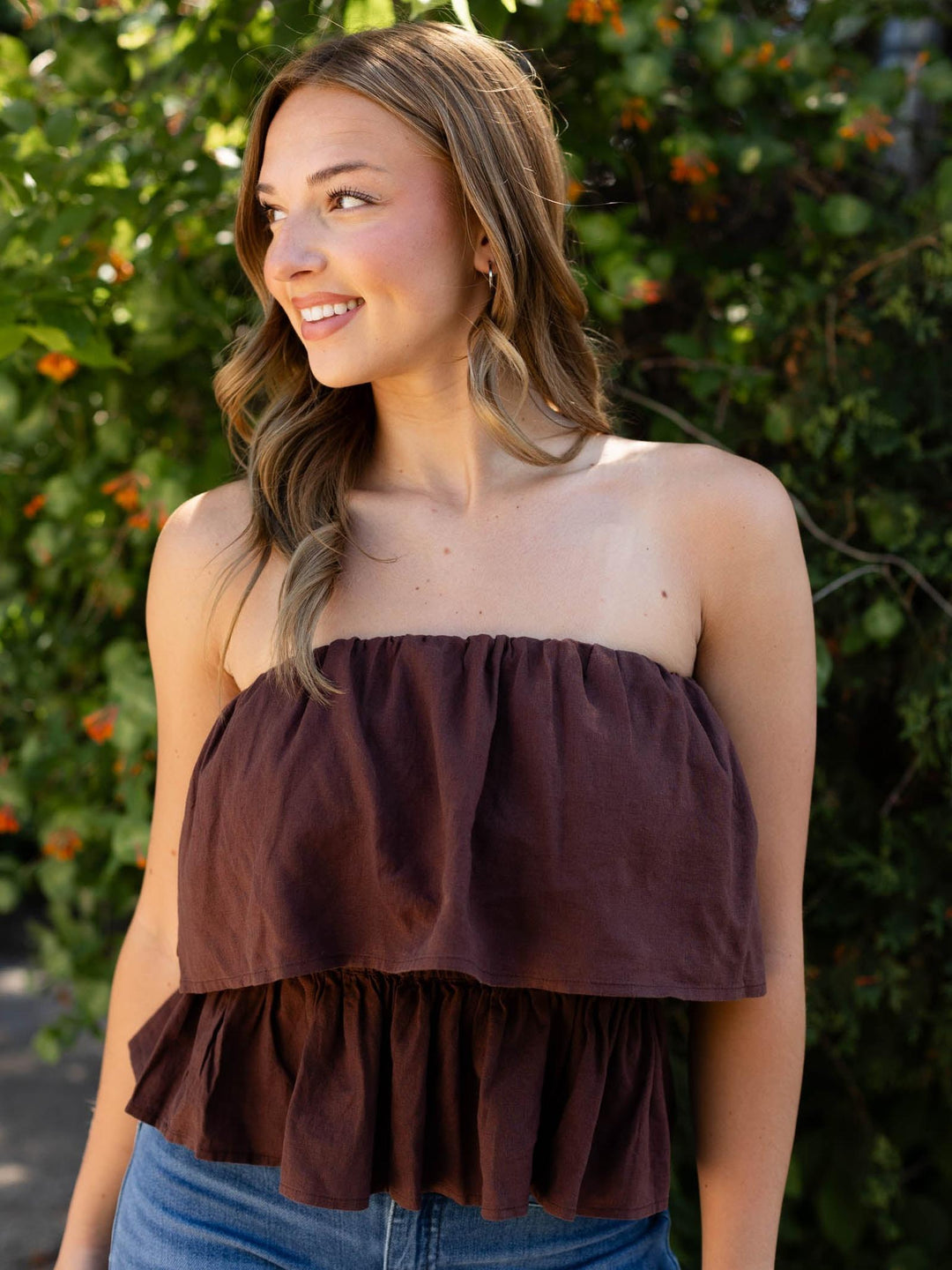 Smiling model in a Chocolate Cherry Z Supply Mabel strapless ruffled top with a fitted waist.
