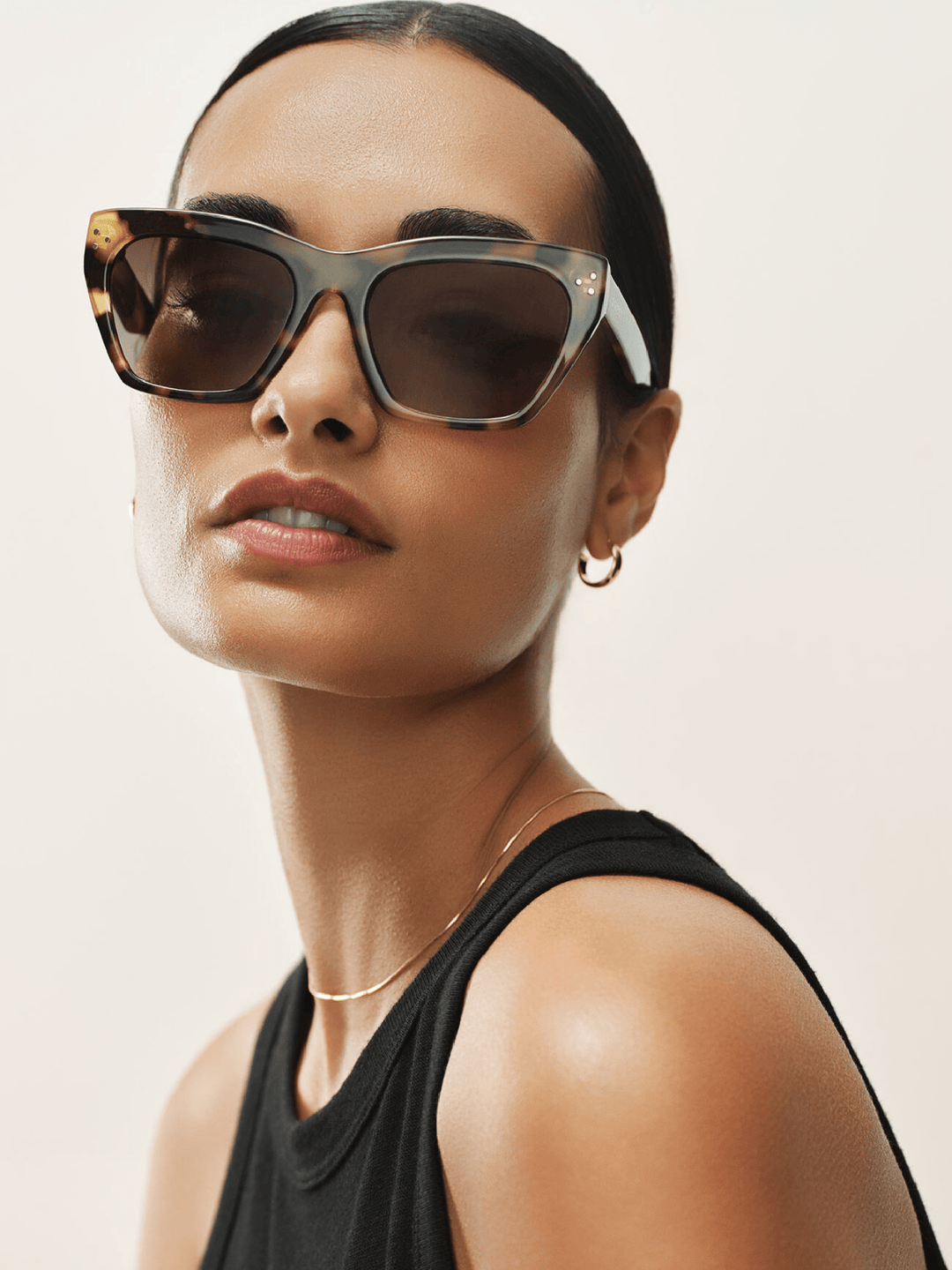 Woman wearing stylish sunglasses with a neutral background