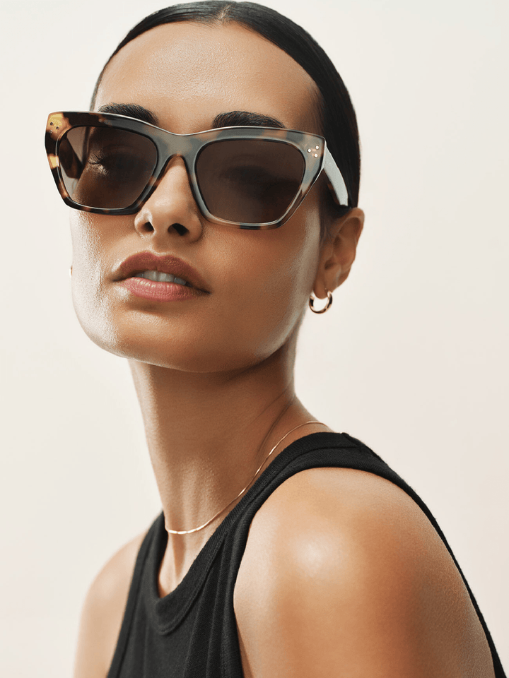 Woman wearing stylish sunglasses with a neutral background