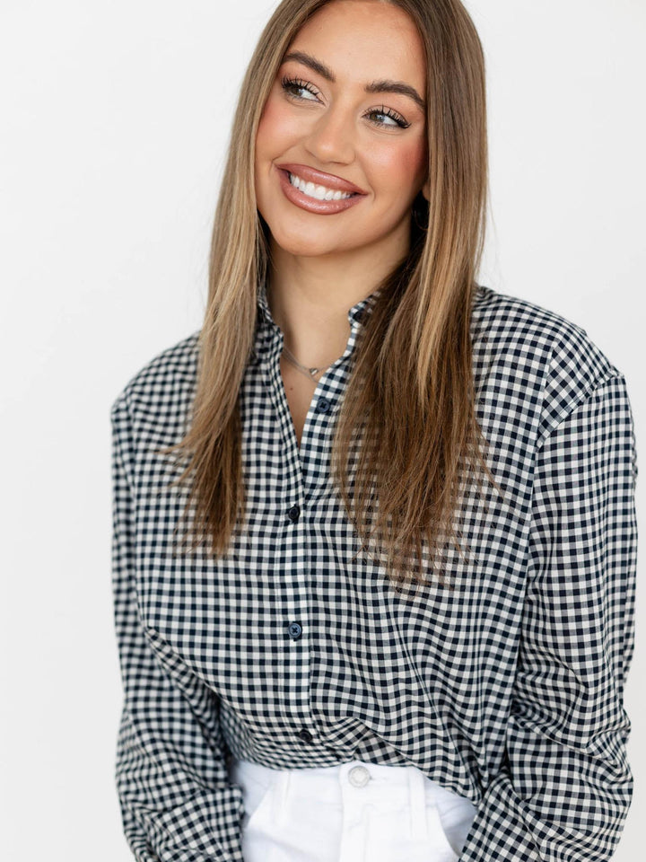 Woman wearing a black and white checkered shirt against a plain background