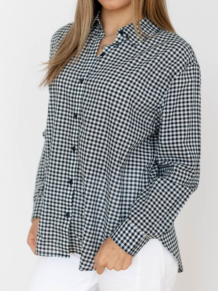 Person wearing a black and white checkered shirt against a plain background