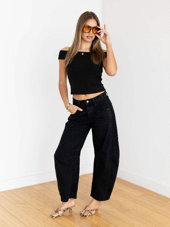 Woman wearing a black outfit with sunglasses against a white background