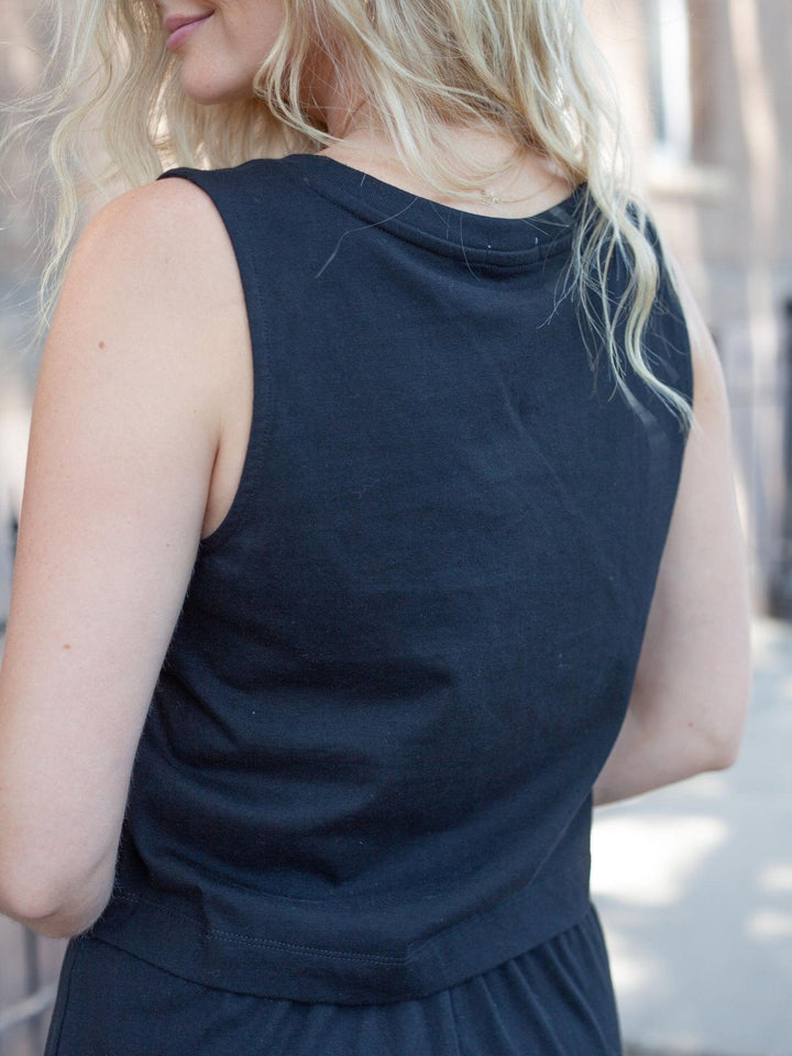 A close-up back view of a woman wearing a sleeveless dark navy top, showing the fabric texture and neckline.