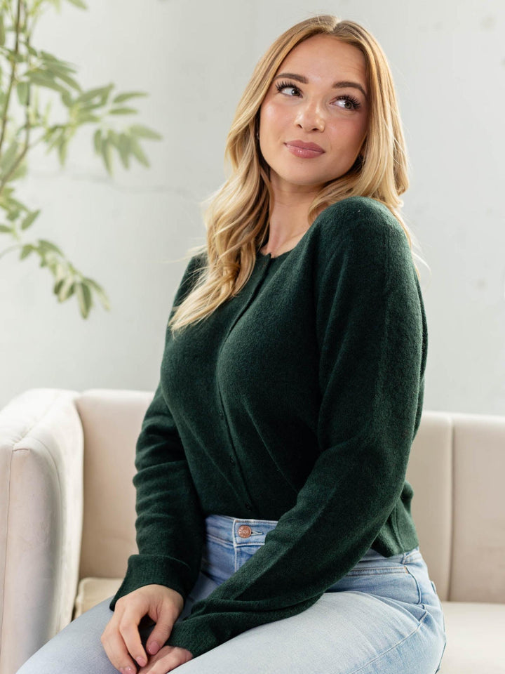 Woman wearing a green sweater sitting on a couch with a light background