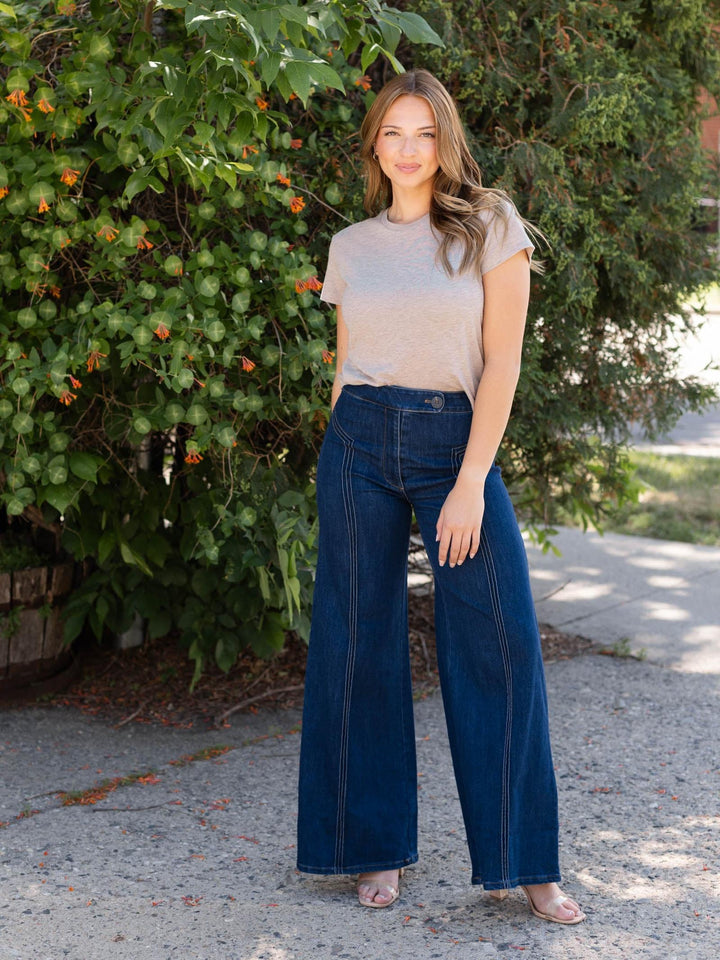 Woman wearing a light brown Z Supply Tourist Tee with a slightly boxy fit and crew neck, paired with dark wash wide-leg jeans.